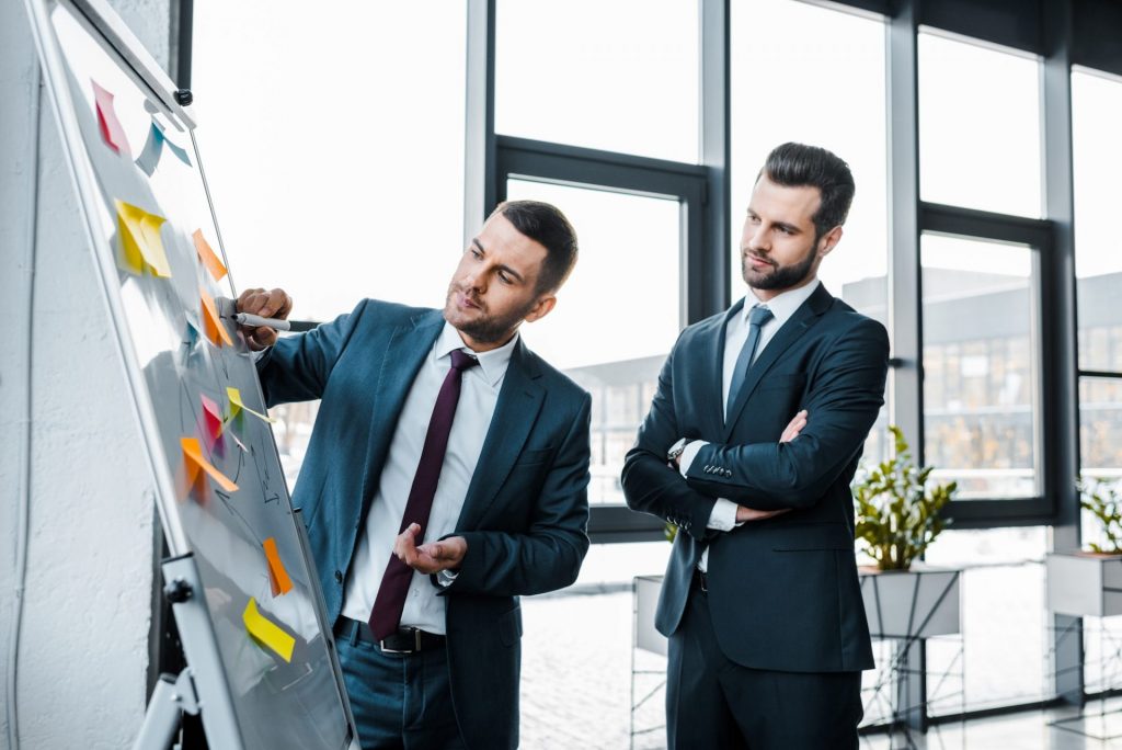 handsome businessmen looking at white board in modern office